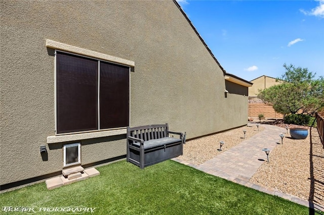 view of side of home featuring stucco siding and fence