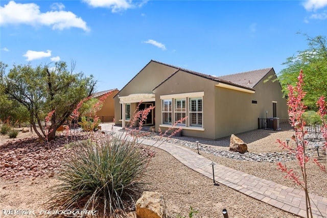 rear view of property with stucco siding, fence, and a patio