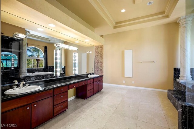 1008 Trophy Hills Dr, Las Vegas, NV 89134 - bathroom with double vanity, a sink, a tray ceiling, decorative columns, and baseboards