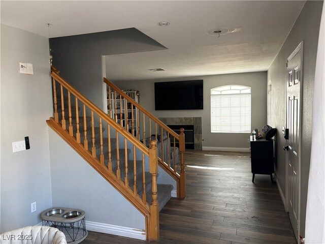 5024 Starfinder Ave, Las Vegas, NV 89108 - staircase featuring wood finished floors, a tile fireplace, and baseboards