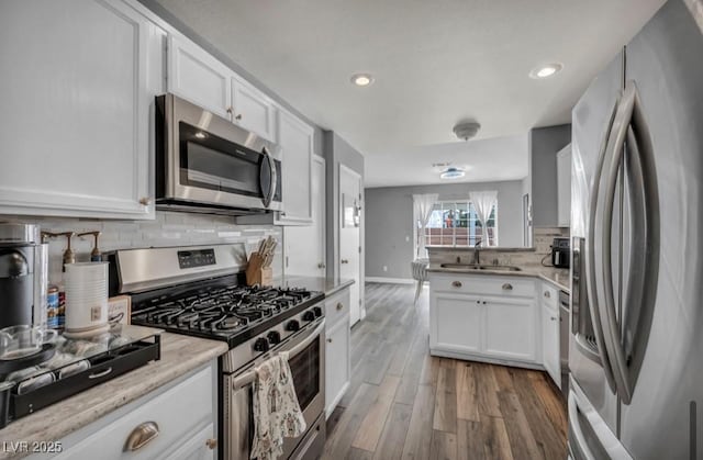 5024 Starfinder Ave, Las Vegas, NV 89108 - kitchen with stainless steel appliances, wood finished floors, a sink, decorative backsplash, and white cabinetry