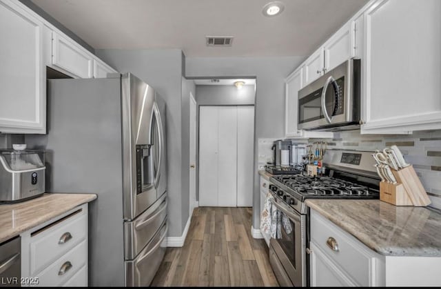 5024 Starfinder Ave, Las Vegas, NV 89108 - kitchen featuring appliances with stainless steel finishes, wood finished floors, white cabinets, decorative backsplash, and light stone counters