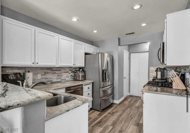 5024 Starfinder Ave, Las Vegas, NV 89108 - kitchen featuring appliances with stainless steel finishes, white cabinetry, a sink, light stone countertops, and tasteful backsplash