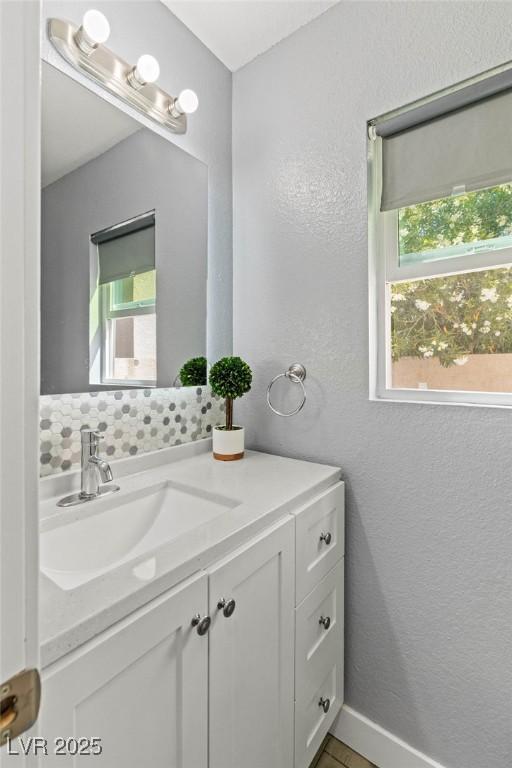 bathroom featuring vanity, a textured wall, and a healthy amount of sunlight