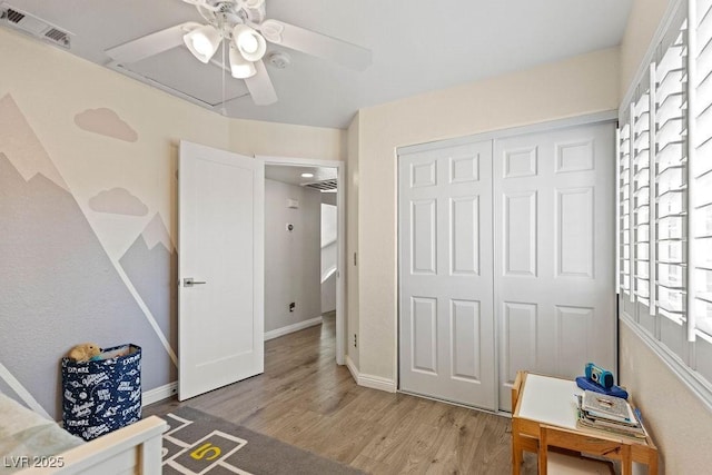 bedroom with a closet, wood finished floors, visible vents, ceiling fan, and baseboards