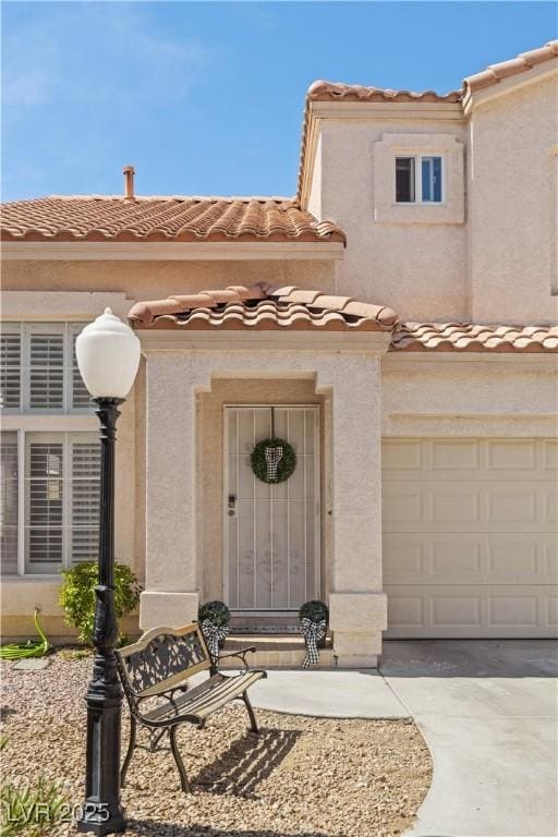 view of exterior entry featuring stucco siding, a garage, and a tiled roof
