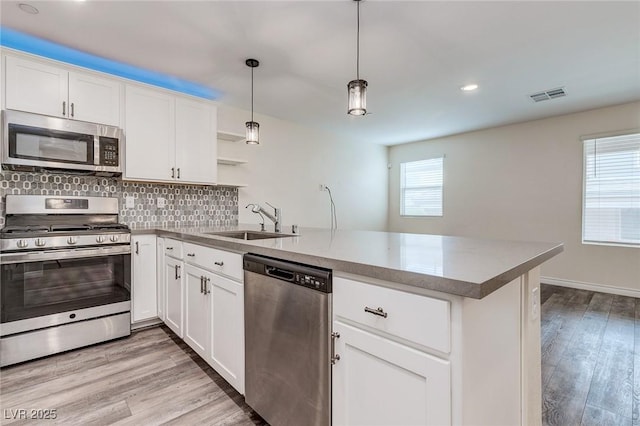 kitchen featuring a sink, a peninsula, stainless steel appliances, visible vents, and a wealth of natural light
