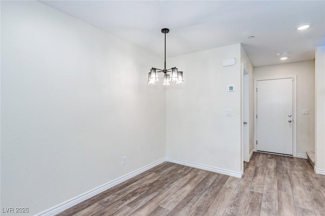 unfurnished dining area with recessed lighting, wood finished floors, baseboards, and a notable chandelier