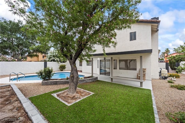 rear view of property with a lawn, a fenced in pool, a patio area, stucco siding, and a fenced backyard