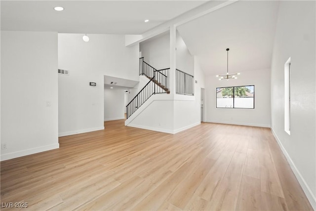 unfurnished living room with light wood finished floors, high vaulted ceiling, visible vents, a chandelier, and stairs