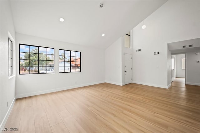 unfurnished living room featuring light wood-type flooring, baseboards, visible vents, and high vaulted ceiling