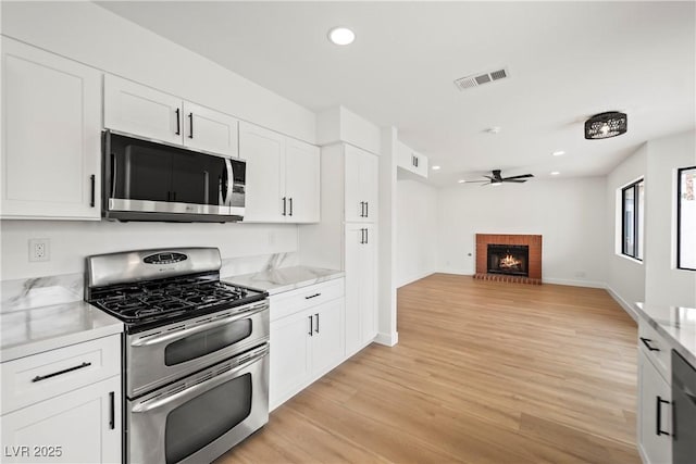 kitchen featuring a ceiling fan, light wood-style flooring, visible vents, white cabinetry, and stainless steel appliances