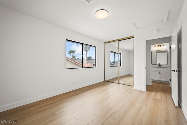 unfurnished bedroom with a closet, light wood-type flooring, and baseboards
