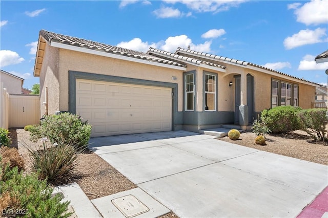 view of front facade with concrete driveway, a garage, a tiled roof, and stucco siding