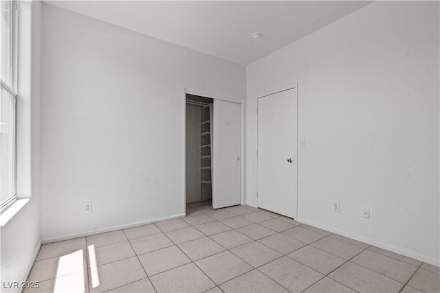 unfurnished bedroom with light tile patterned floors, baseboards, and a closet