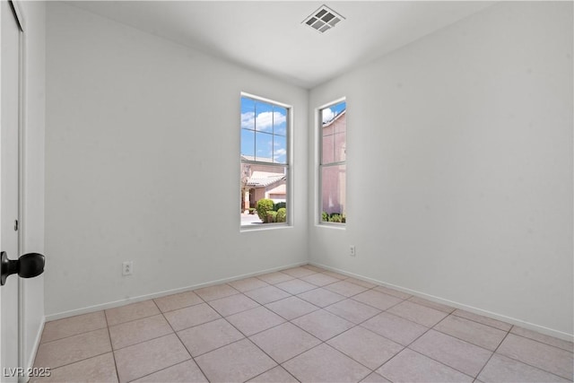 spare room with light tile patterned floors and baseboards