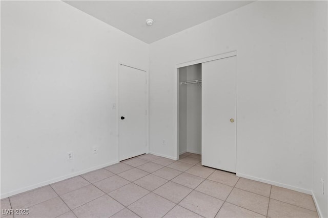 unfurnished bedroom featuring light tile patterned floors, a closet, and baseboards