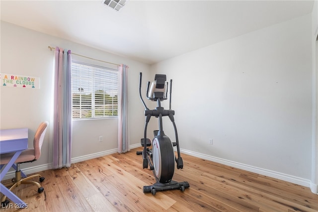 workout area featuring baseboards, light wood-style floors, and visible vents