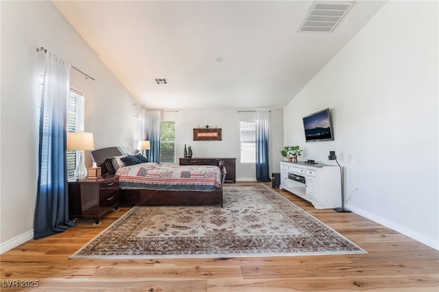 bedroom featuring light wood finished floors, visible vents, and baseboards