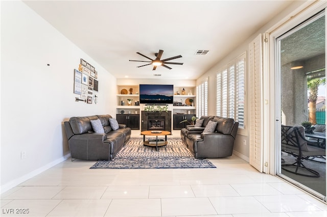 living room with a ceiling fan, baseboards, light tile patterned floors, visible vents, and built in features