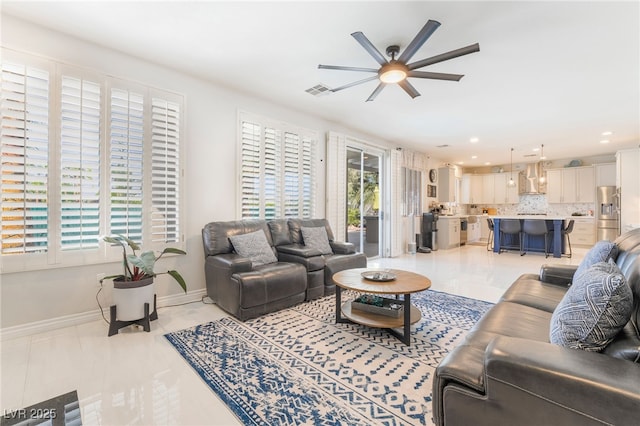 living area featuring baseboards, a ceiling fan, a healthy amount of sunlight, and recessed lighting