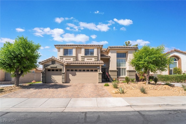 mediterranean / spanish-style house with a tile roof, an attached garage, stucco siding, and decorative driveway