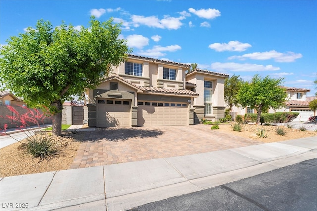 view of front of house with fence, a tile roof, a garage, stucco siding, and decorative driveway