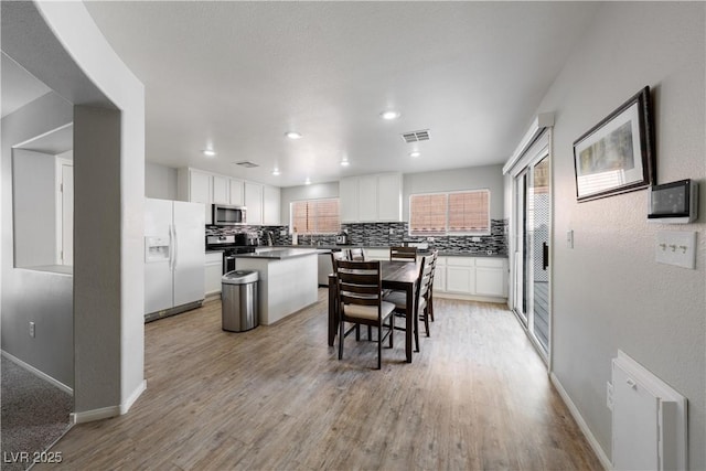 kitchen with a wealth of natural light, appliances with stainless steel finishes, a kitchen island, and backsplash
