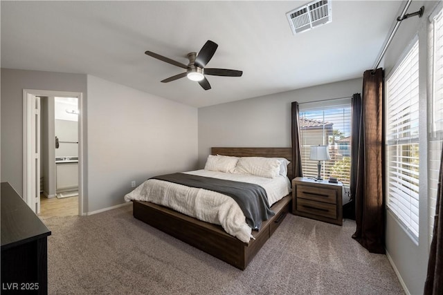 bedroom with ensuite bathroom, visible vents, baseboards, ceiling fan, and light carpet
