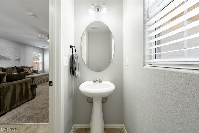 bathroom featuring a ceiling fan, baseboards, a sink, and wood finished floors