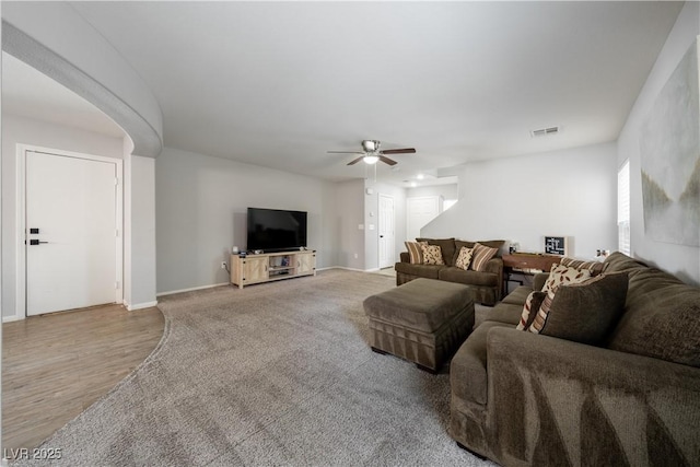 living area with wood finished floors, visible vents, baseboards, and ceiling fan