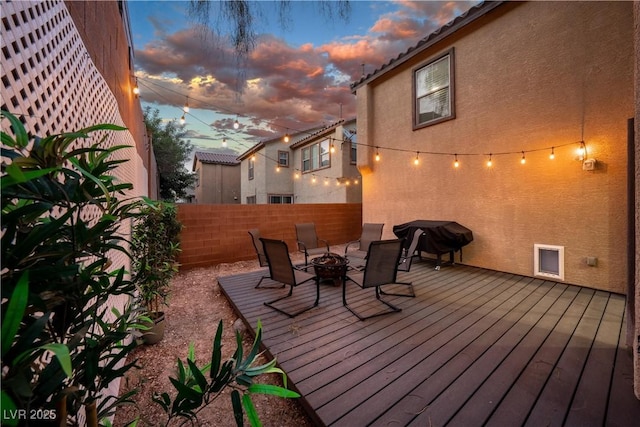 deck with an outdoor fire pit, fence, and area for grilling