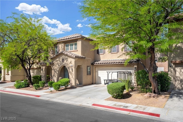 mediterranean / spanish-style house with a tile roof, concrete driveway, a garage, and stucco siding