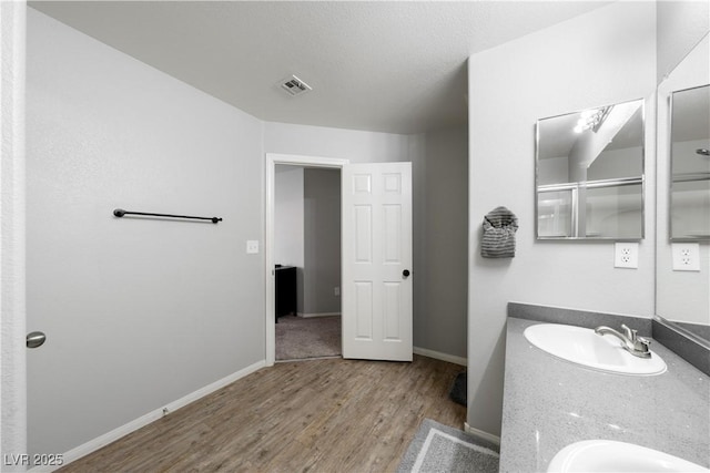 full bathroom featuring baseboards, visible vents, a sink, double vanity, and wood finished floors