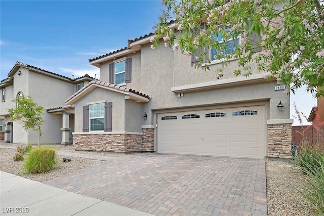2486 Dragon Fire Ln, Henderson, NV 89052 - view of front facade with stone siding, an attached garage, a tiled roof, stucco siding, and decorative driveway
