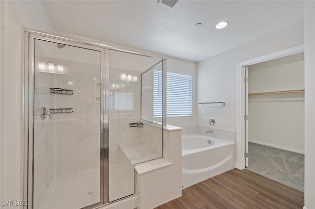 2486 Dragon Fire Ln, Henderson, NV 89052 - bathroom featuring wood finished floors, visible vents, a stall shower, a spacious closet, and a garden tub