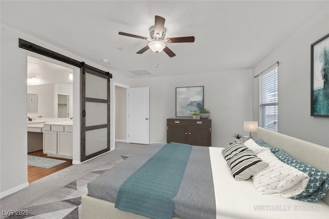2486 Dragon Fire Ln, Henderson, NV 89052 - bedroom with a barn door, light colored carpet, ensuite bathroom, and a ceiling fan