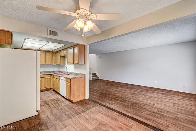 kitchen featuring a sink, light wood-type flooring, visible vents, white appliances, and light countertops