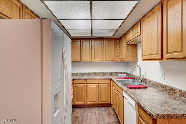 kitchen with a sink, white appliances, visible vents, and wood finished floors