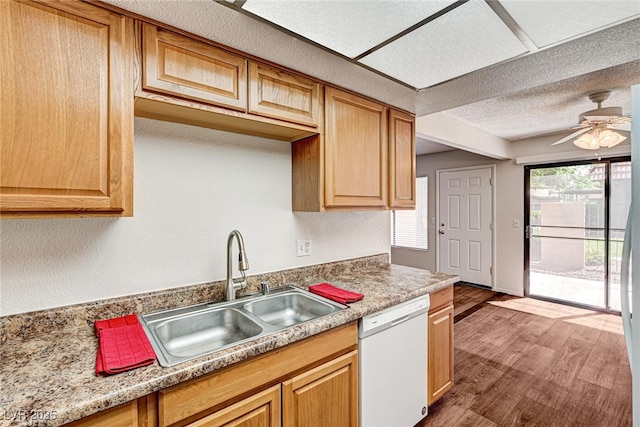 kitchen with light countertops, wood finished floors, a sink, ceiling fan, and dishwasher