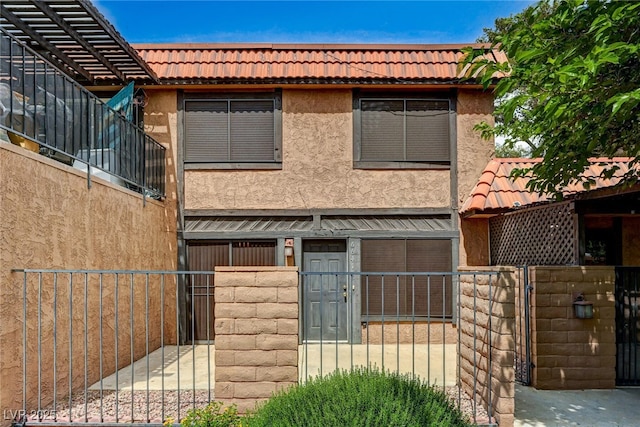 view of front of home featuring a tile roof, stucco siding, a gate, and a fenced front yard