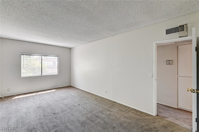 unfurnished room with a textured ceiling, carpet, and visible vents