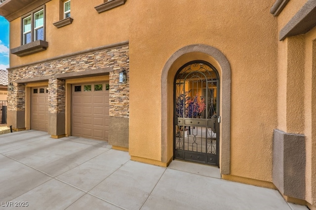 409 Lake Windemere St, Las Vegas, NV 89138 - view of exterior entry with stone siding, stucco siding, a garage, and driveway