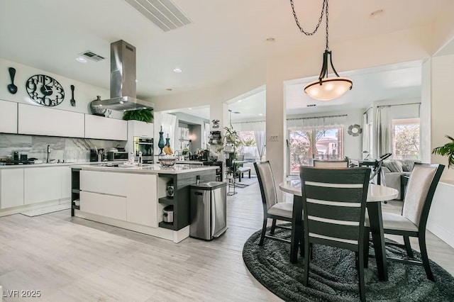 10408 Mezzanino Ct, Las Vegas, NV 89135 - kitchen featuring island exhaust hood, visible vents, decorative backsplash, white cabinets, and modern cabinets