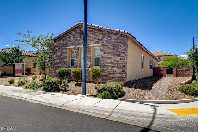 2425 Amatrice St, Henderson, NV 89044 - view of property exterior with stone siding, stucco siding, a tile roof, and fence
