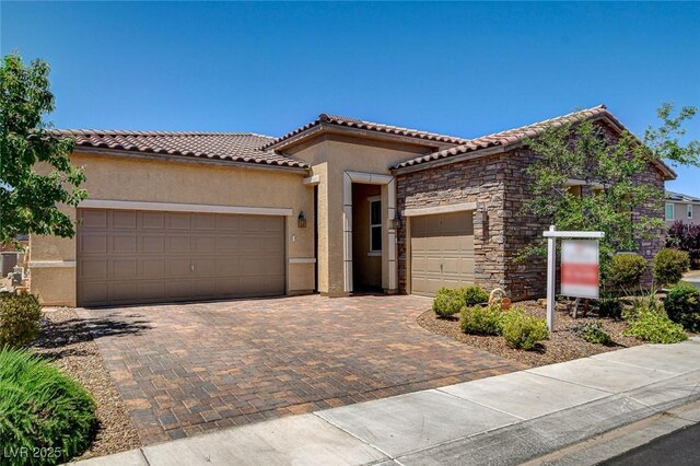 2425 Amatrice St, Henderson, NV 89044 - mediterranean / spanish house with stone siding, stucco siding, decorative driveway, and a garage