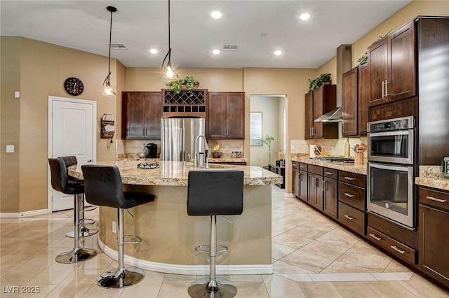 2425 Amatrice St, Henderson, NV 89044 - kitchen with a center island with sink, appliances with stainless steel finishes, decorative backsplash, and a kitchen bar