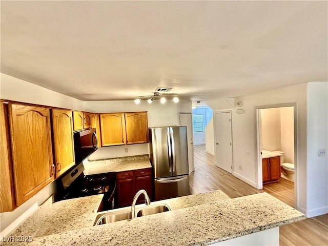 2524 Charleville Ave Unit 102, Las Vegas, NV 89106 - kitchen featuring light wood finished floors, a peninsula, a sink, stainless steel appliances, and light stone counters