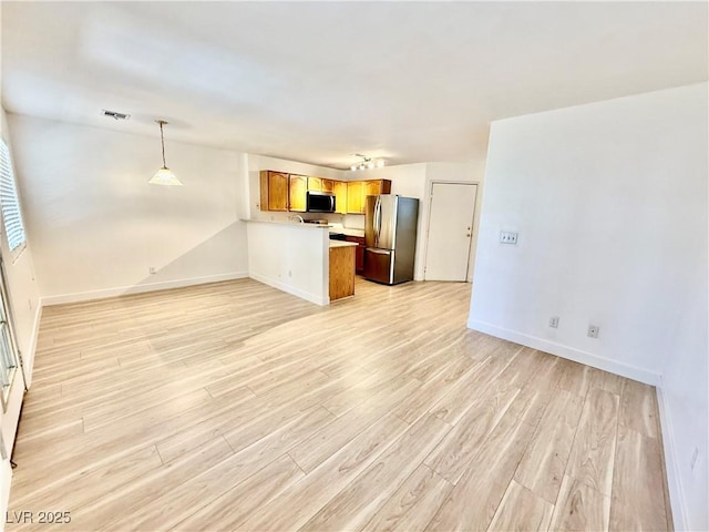 2524 Charleville Ave Unit 102, Las Vegas, NV 89106 - kitchen featuring a peninsula, light wood finished floors, brown cabinetry, open floor plan, and appliances with stainless steel finishes