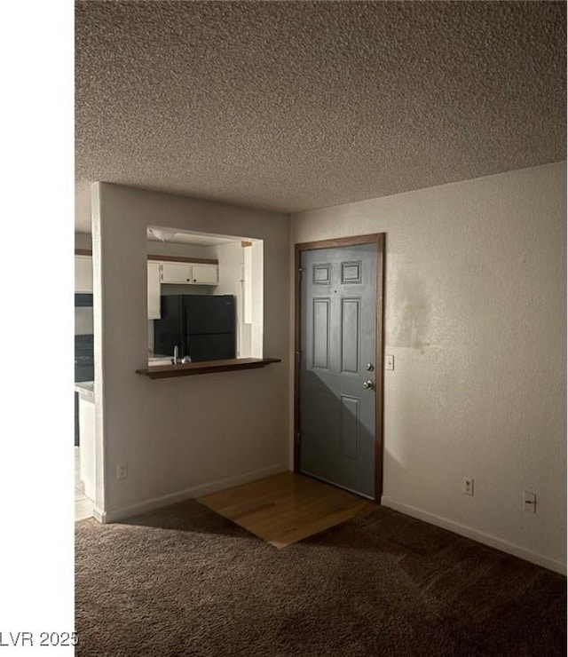 carpeted foyer entrance with a textured ceiling and baseboards